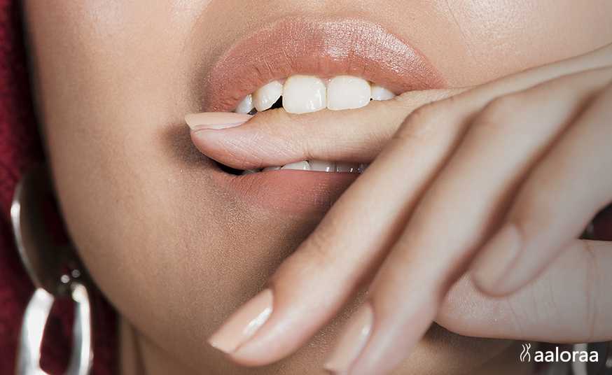 Face of woman with her finger between her teeth